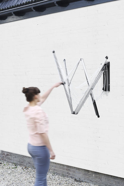 "Vista laterale dello stendibiancheria da parete Brabantia con vestiti appesi"